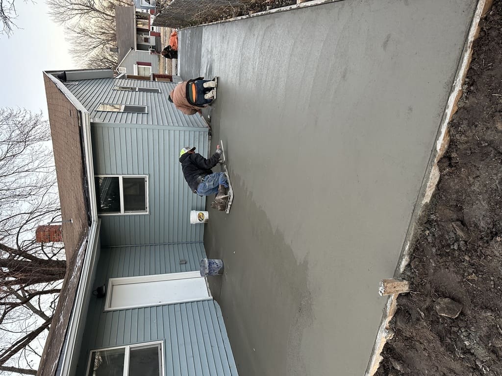 concrete slab and sidewalk freshly poured in a backyard right outside of the house.