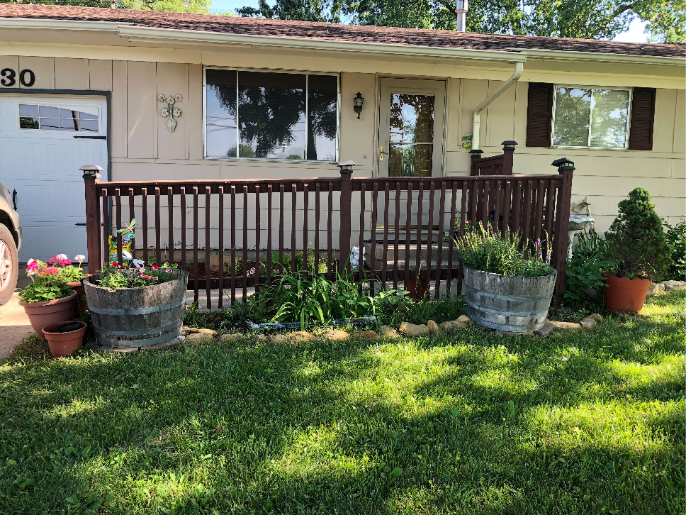 a new flower bed being planted with flowers and mulch in front of a house