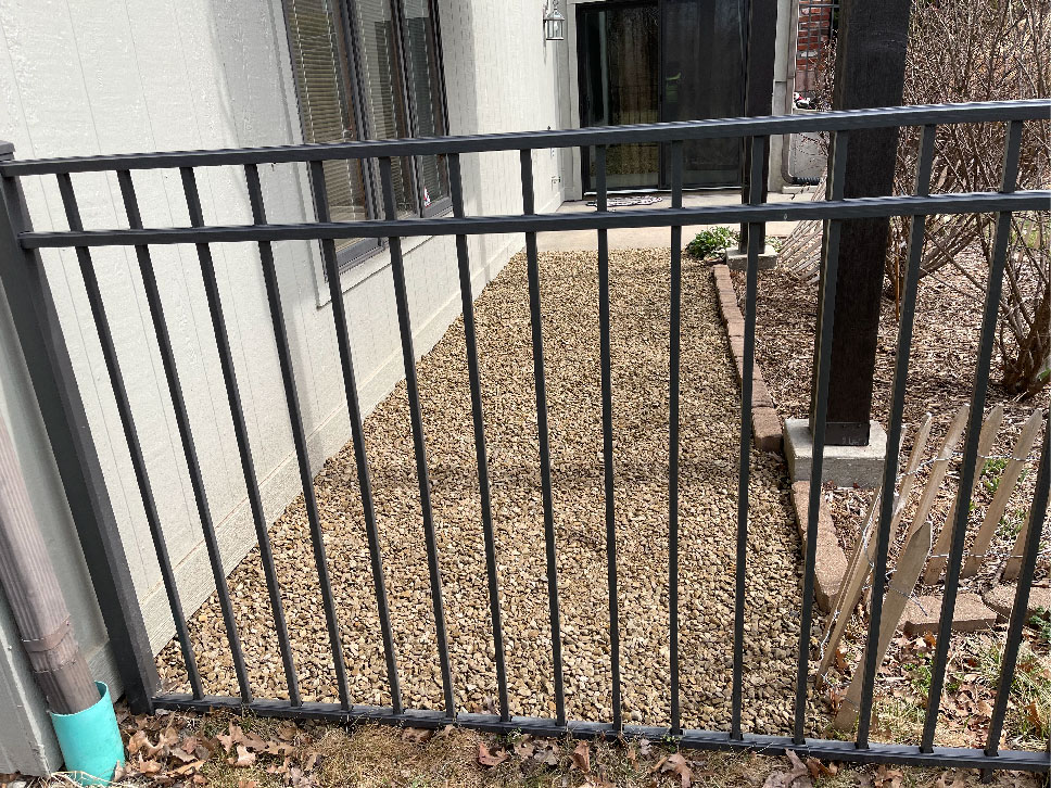 a new stone bed in the backyard behind a metal fence